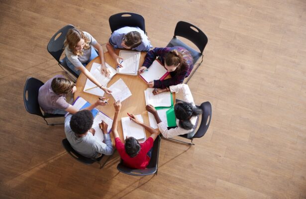 Overhead Shot Of High School Pupils In Group Study Around Tables